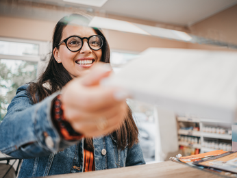 Woman smiles while paying for medication at pharmacy.
