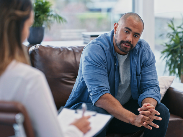 young man looking thoughtful while sitting in session with his therapist