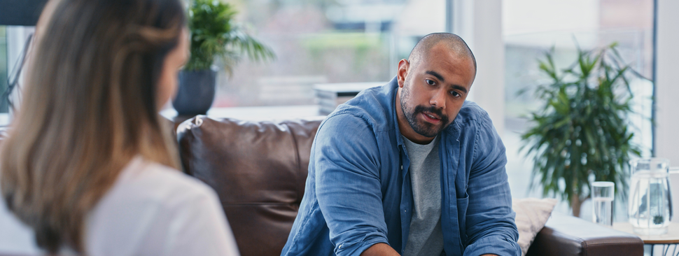 young man looking thoughtful while sitting in session with his therapist