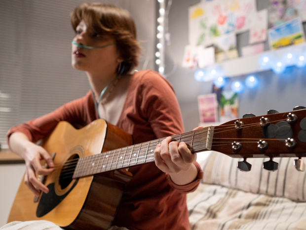 teenage girl playing guitar in her room