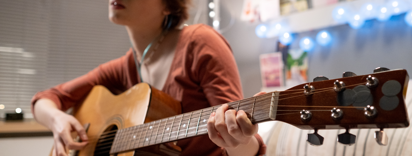 teen girl playing guitar sitting on her hospital bed