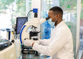 A lab technician looks at slides on a microscope