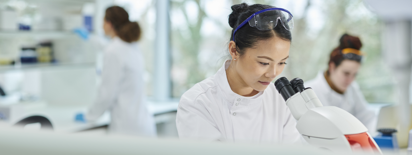 Female clinical researcher looking in microscope.