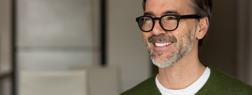 An older man smiles into the camera