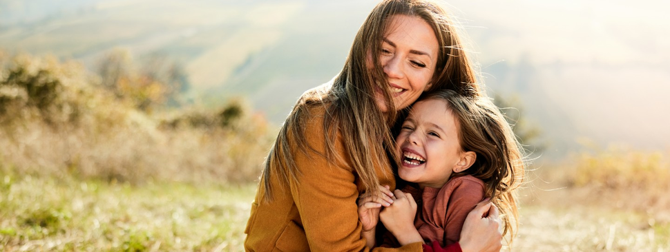 Cheerful single mother and daughter having fun in autumn day