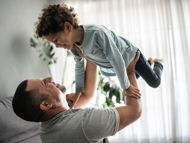 Father holds up toddler son in the air.