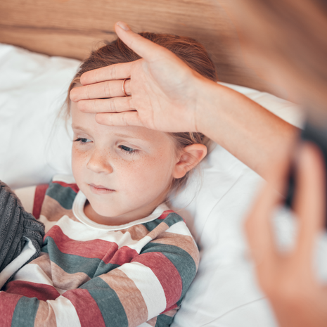 mom checking young girl’s temperature
