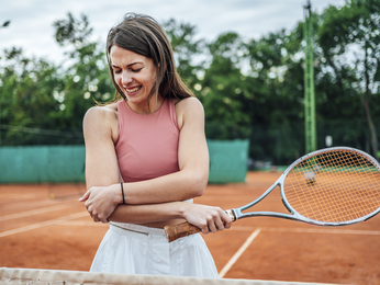Young woman injured elbow during tennis practice