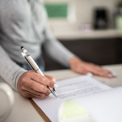 Closeup of woman hand filling document in kitchen at home