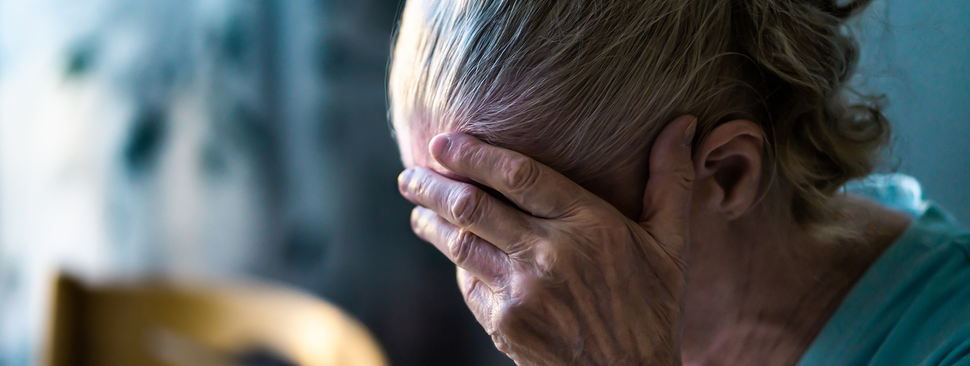 A mature woman holds her head