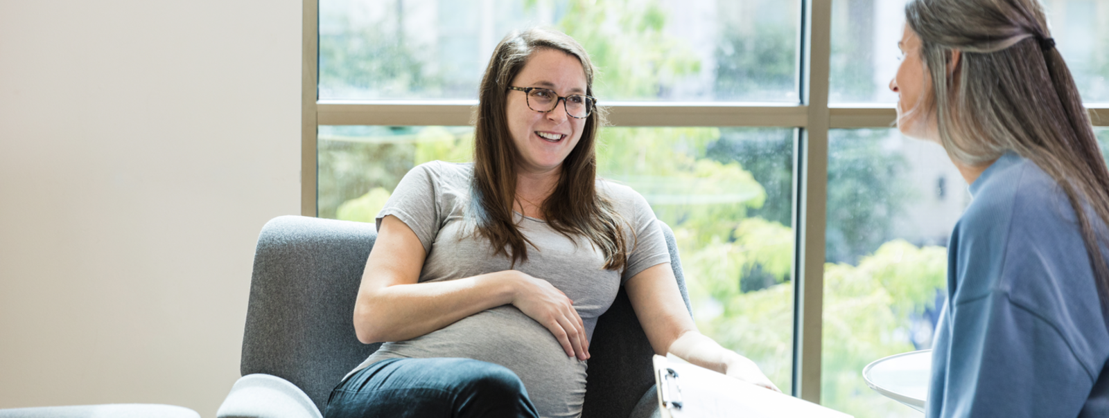 A pregnant woman sits on a sofa