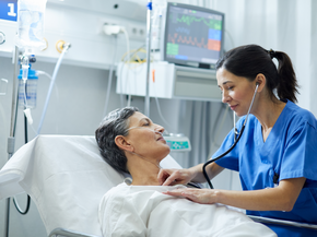 Female nurse helping senior patient lying in a hospital bed