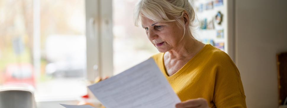 Two women sit at a desk, talking and writing notes