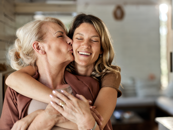 Mother kissing adult daughter on the cheek