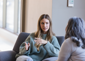 A girl talks with her hands while seated with a medical professional
