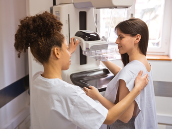 Woman in hospital gown prepares for mammogram