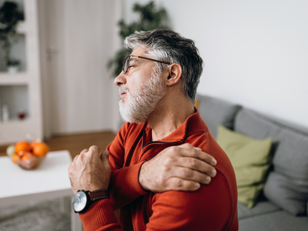 Man in discomfort who is holding his shoulder 
