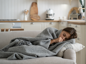 Adolescent girl laying on the couch, coughing and not feeling well