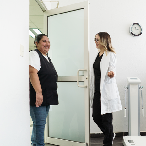 A health care provider opens the door and welcomes a patient.