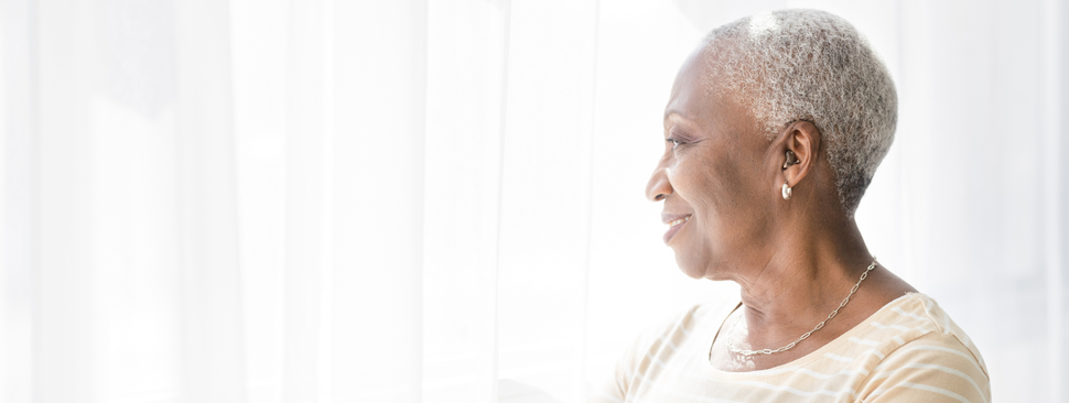 Older woman with a hearing aid standing near a window