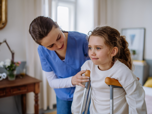 Nurse helping girl on crutches