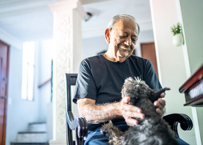 A man in a wheelchair smiles at a small dog