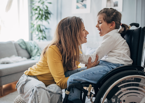 A mother smiles at her child, who is in a wheelchair