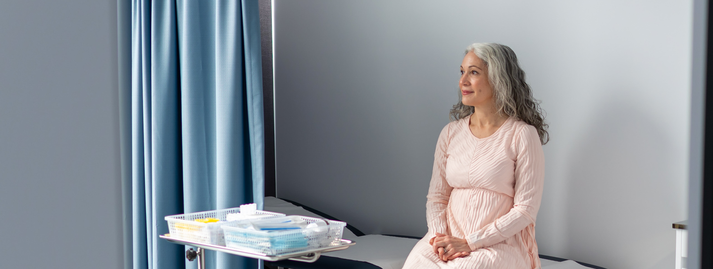 A mature age woman with grey hair, sits alone in a medical clinic.
