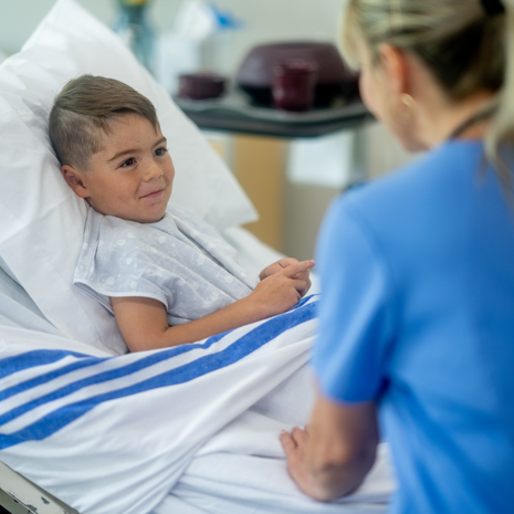 Female nurse sits at the bedside of a young male patient