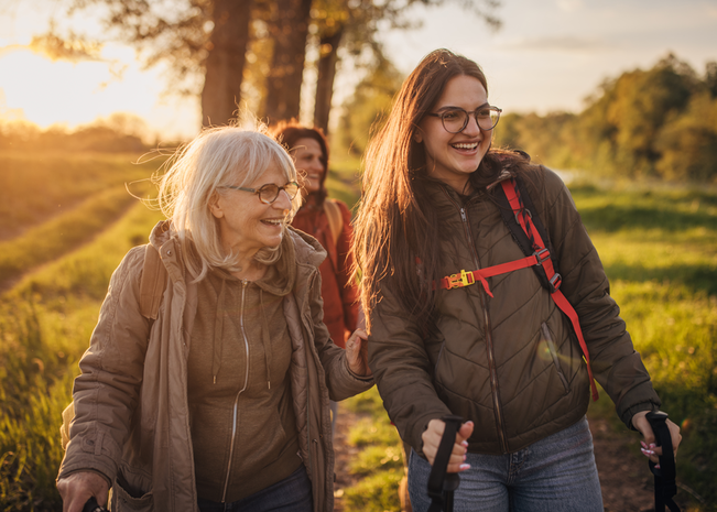 A young adult walks with her grandmother on a trail outdoors