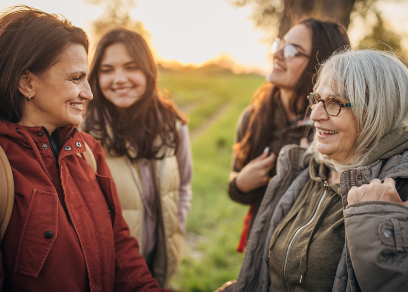 A group of women wearing backpacks smile outdoors