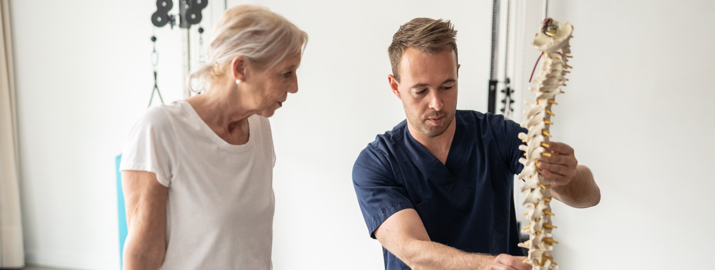 doctor showing elderly patient a model spine