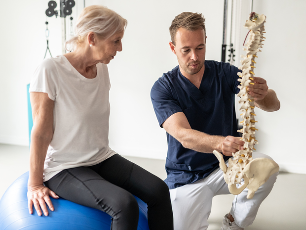 doctor showing elderly patient a model spine