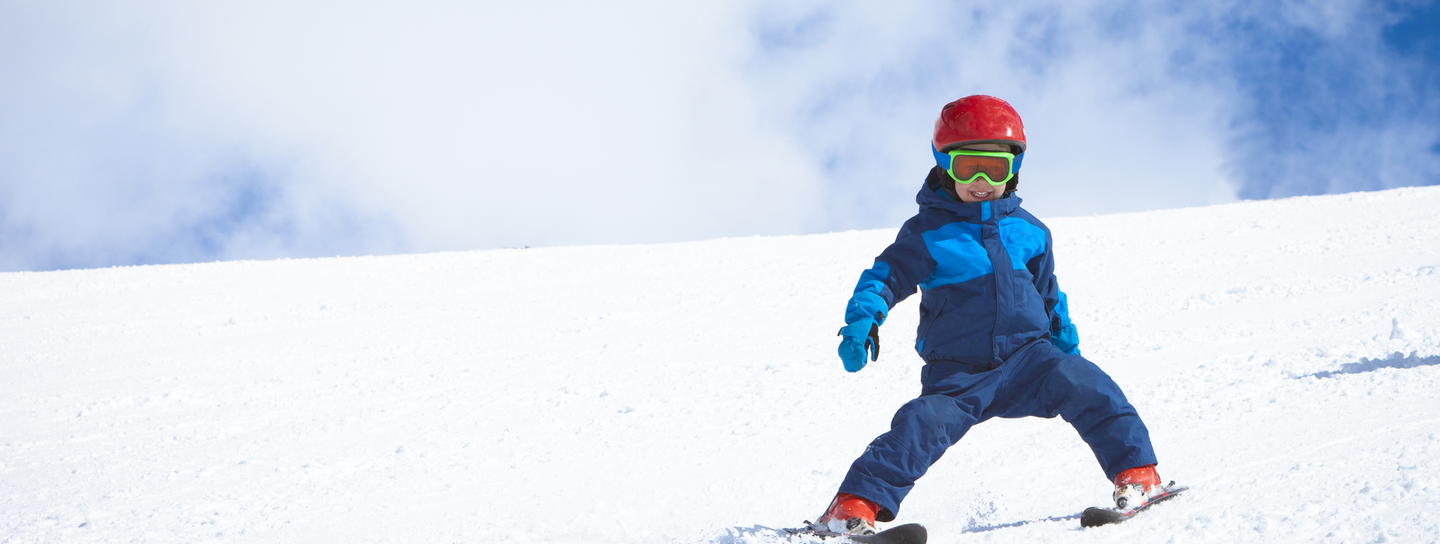 Two children laying in snow on ski hill.