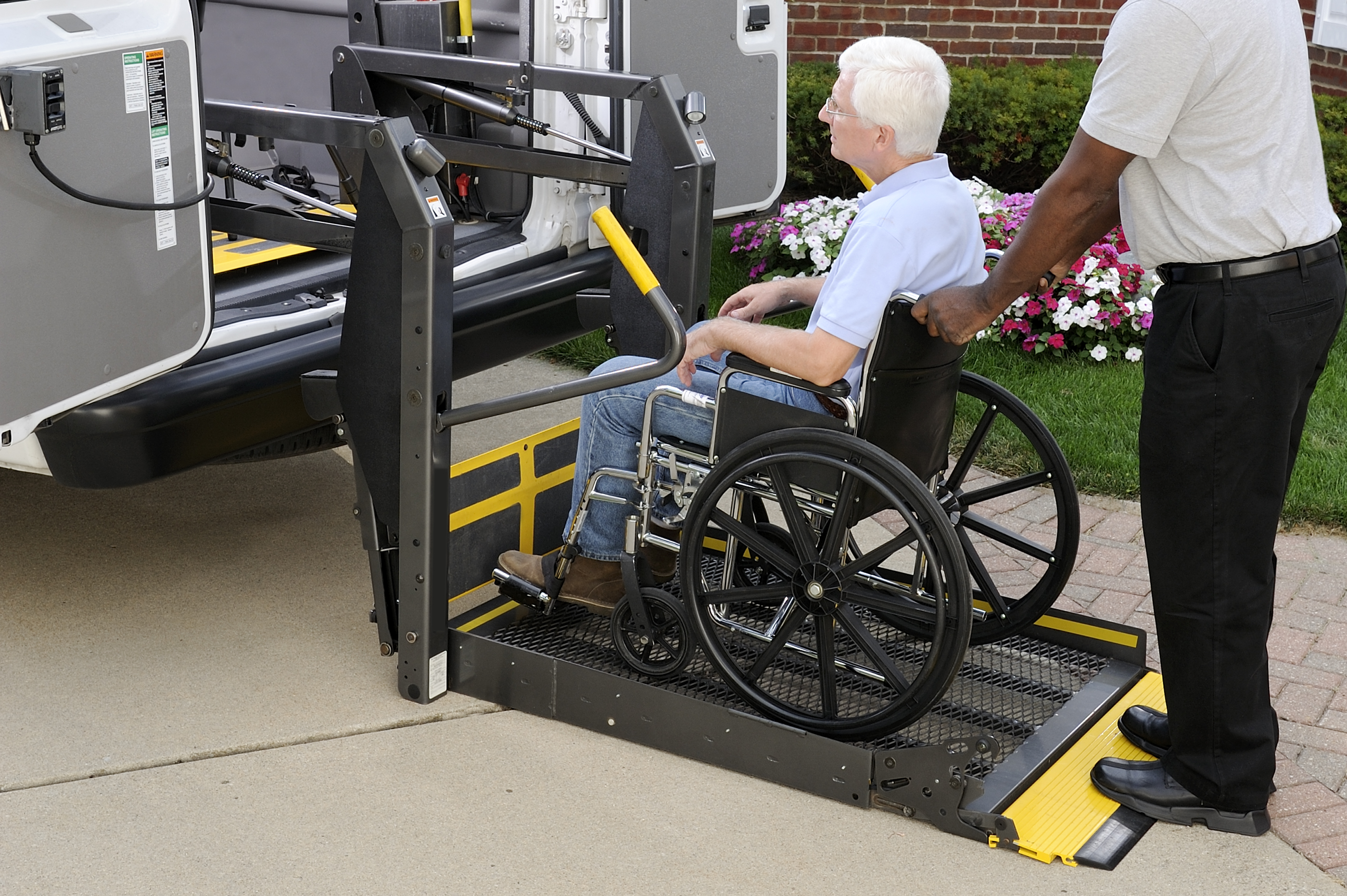 Senior man in a wheelchair being loaded into a bus using an elevator