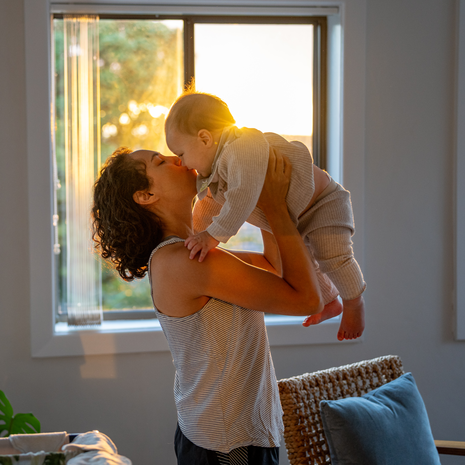 Woman holding her baby up for a kiss