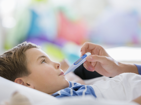 Child on hospital bed with thermometer in mouth