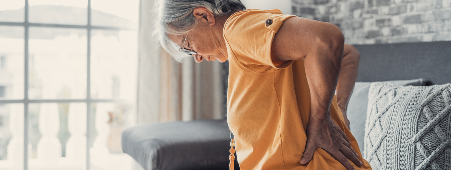 A woman braces her lower back with her hands