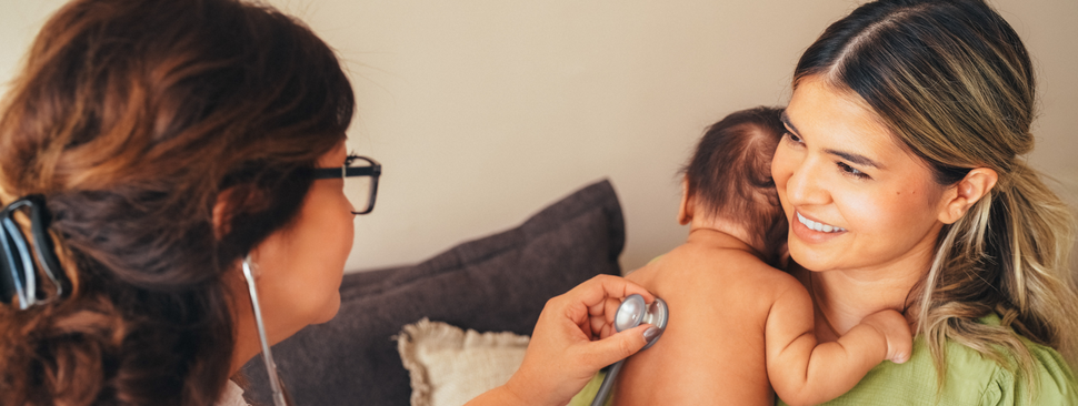 Mom holds her baby while a doctor listens to its heartbeat
