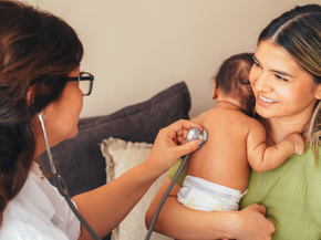 Mom holds her baby while a doctor listens to its heartbeat