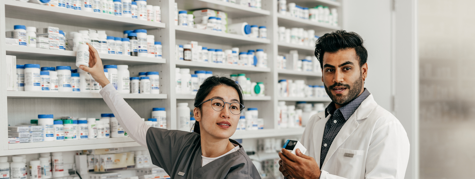 Pharmacist helps customer in pharmacy while resident watches on.