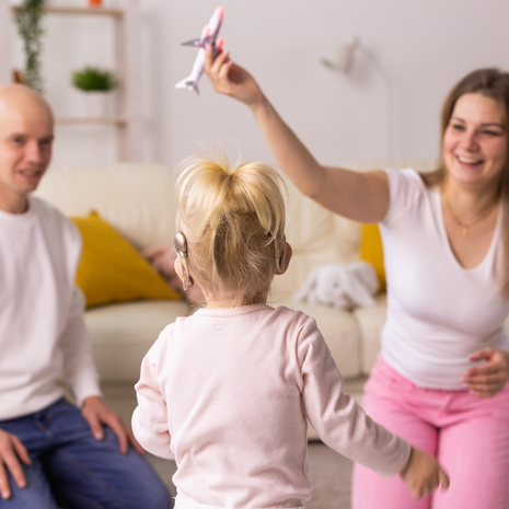 young girl with cochlear implant playing with her parents