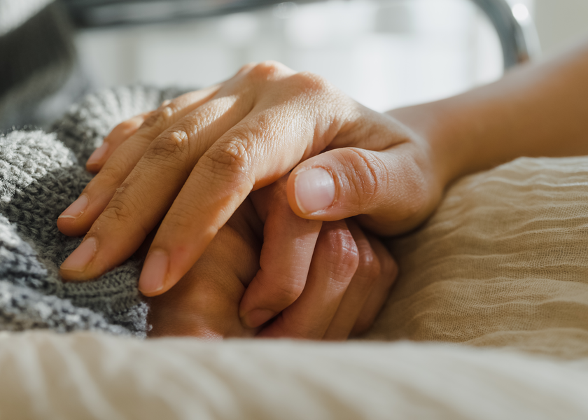 Provider holds hands with hospice patient.
