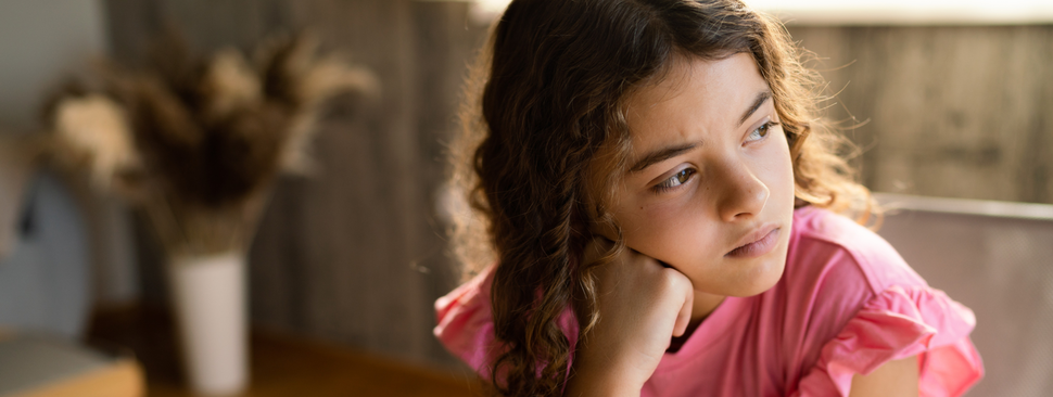 Teenage girl sitting at home thinking