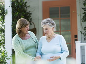 Social worker sits with elderly woman at her home.