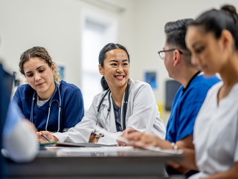 Provider points to chart on tablet with two colleagues.