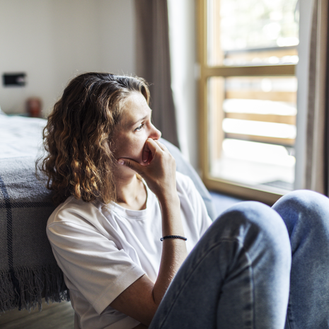 Concerned woman at home looking out a window
