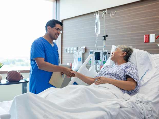 Woman is hospital bed holding prescription bottle.