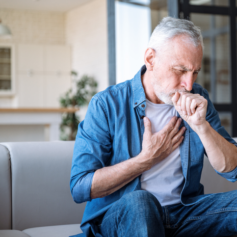 Man coughing with hand on chest