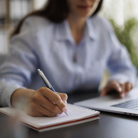 Closeup of person sitting at a desk and writing on notepad